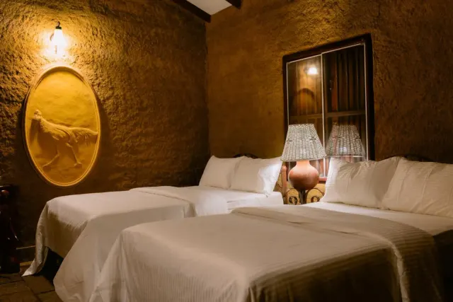 The two double beds in the Economy Quadruple Cottage, with a carved relief in an oval panel on the wall