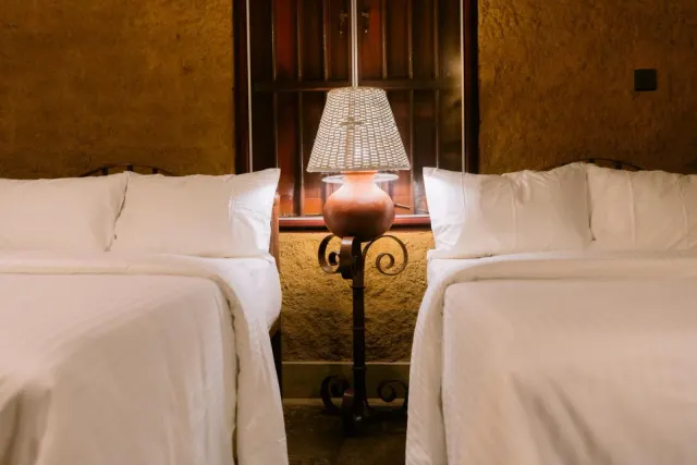 A lamp on a stand between the two double beds in the Economy Quadruple Cottage