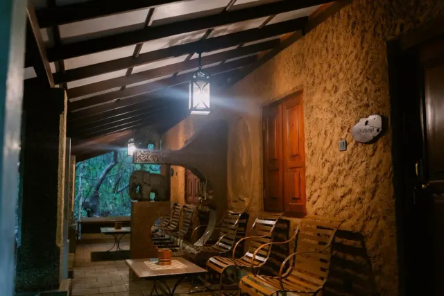 Slatted chairs under the covered roof outside the Economy Quadruple Cottages, lit by a lantern after dark