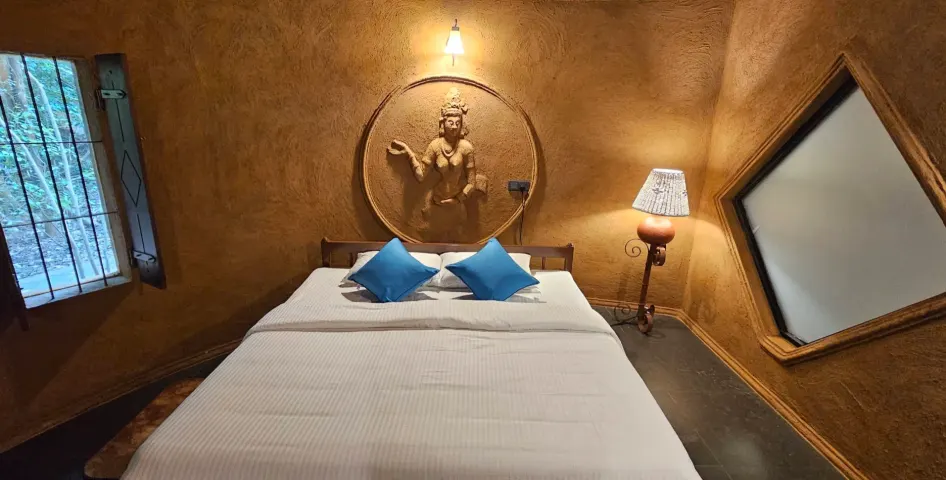 The king bed in the Triple Room Cottage between a barred window and a diamond-shaped window
