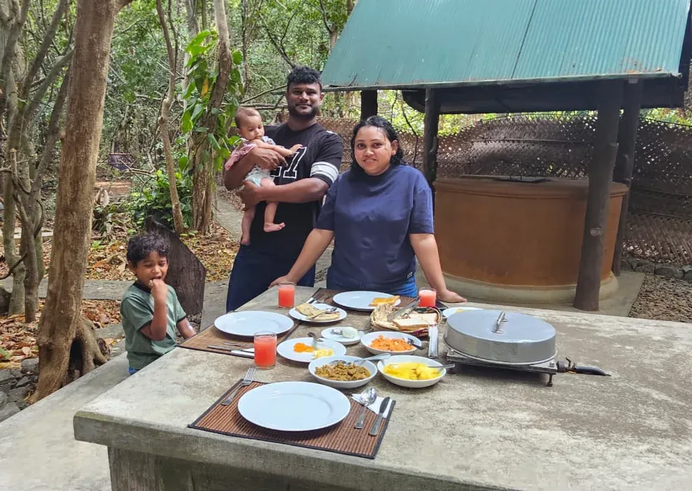 A family at the garden table, breakfast laid out under the tin roof at Sigiriya Wild Cottages