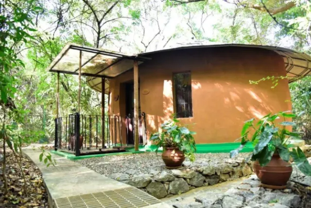 The Triple Room Cottage, a round, mud-walled cottage among the trees at Sigiriya Wild Cottages