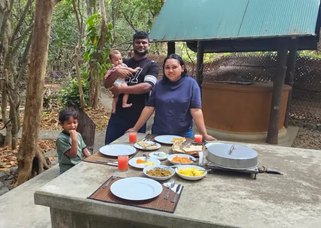 A family at the garden table, breakfast laid out under the tin roof