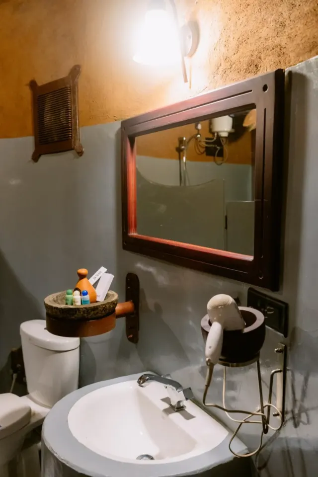 A cottage bathroom with a basin, mirror and toiletries