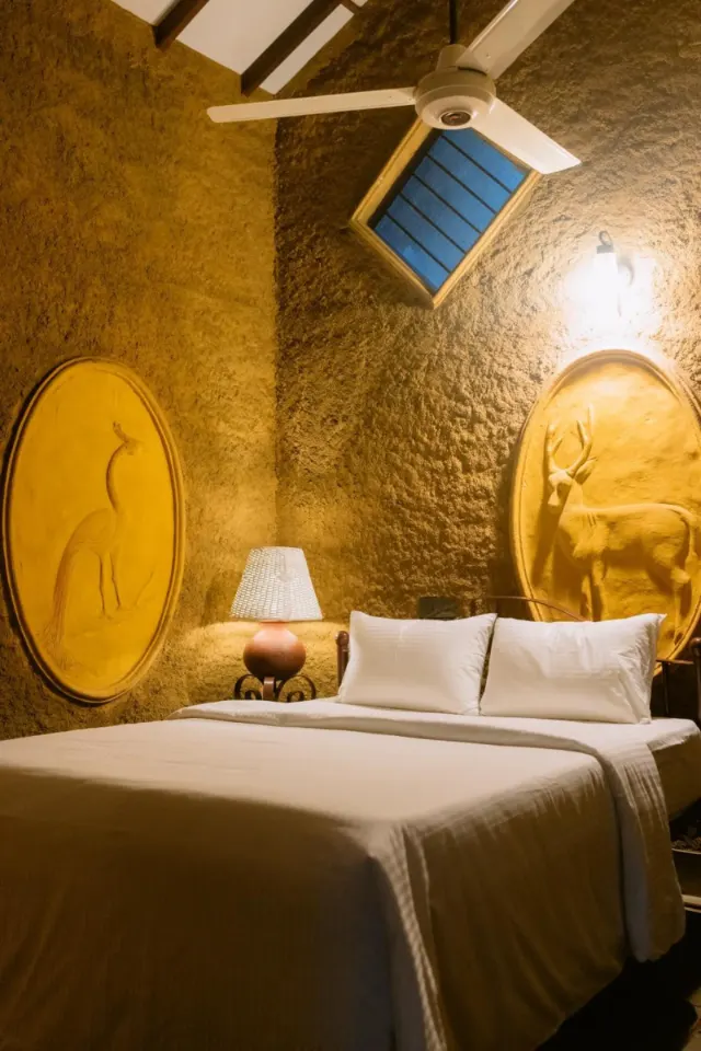 A cottage bedroom with two oval reliefs and a ceiling fan