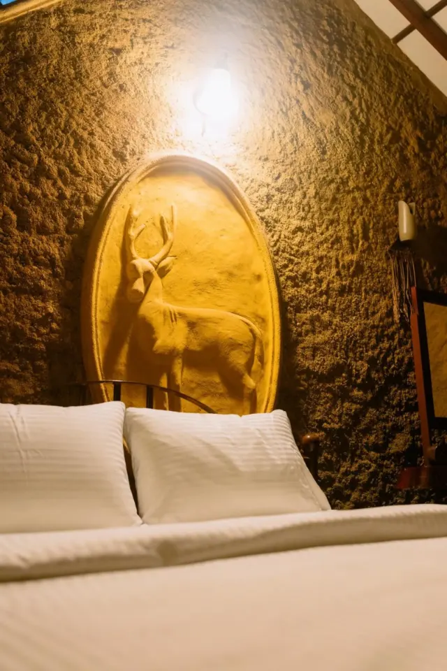 A bed below a deer relief, lit at night