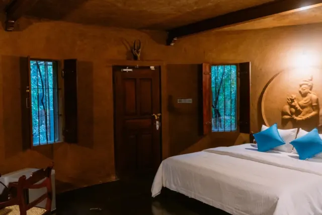 A cottage bedroom with shuttered windows onto the trees