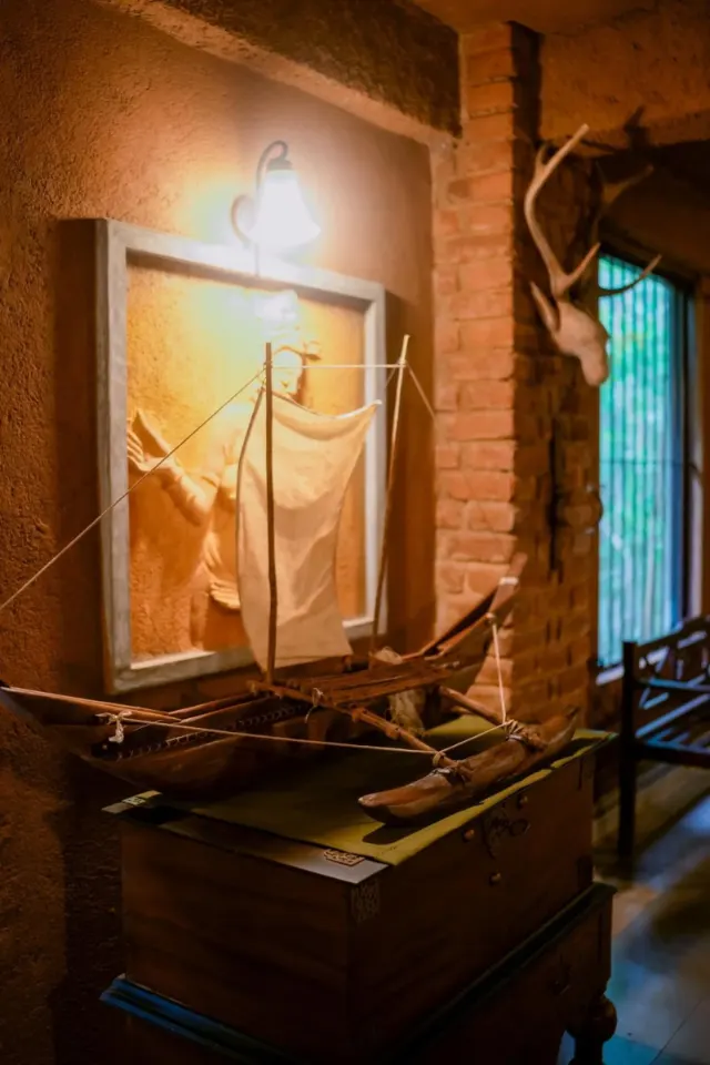 A model outrigger boat below a framed relief