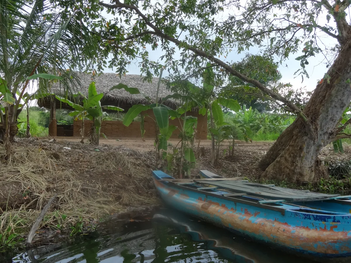 A boat drawn up at the edge of Hiriwadunna lake below a thatched hut